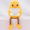 Hand-crocheted Duck doll holding a white positive affirmation sign, sitting on a wooden table.