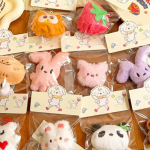 A collection of colorful, assorted mini plush keychain charms arranged neatly, individually packaged.