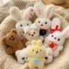 A soft plush character keychain with a built-in squeaker attached to a bag strap.