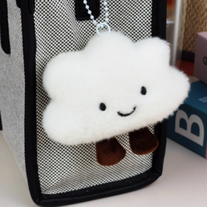 A soft plush character keychain with a built-in squeaker attached to a bag strap.