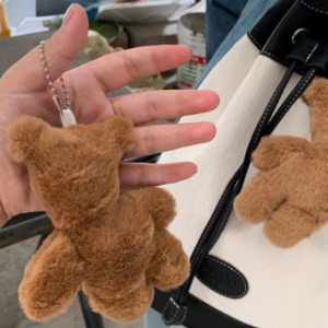 A collection of classic brown plush teddy bear keychains in various quirky styles attached to a bag.