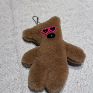 A collection of classic brown plush teddy bear keychains in various quirky styles attached to a bag.
