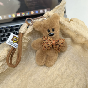A collection of classic brown plush teddy bear keychains in various quirky styles attached to a bag.