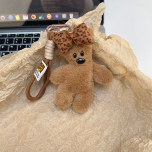 A collection of classic brown plush teddy bear keychains in various quirky styles attached to a bag.